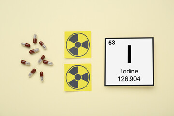 Card with chemical element Iodine, pills and radiation signs on beige background, flat lay