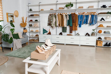 Obraz na płótnie Canvas Stylish clothes with shoes and accessories in light boutique