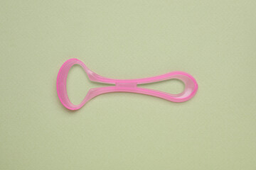 Pink tongue cleaner on olive background, top view