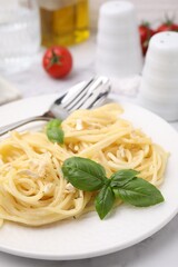 Delicious pasta with brie cheese and basil leaves on white table, closeup