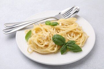 Delicious pasta with brie cheese and basil leaves on light grey table, closeup