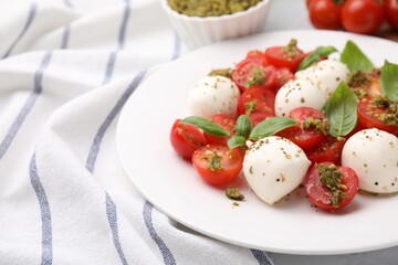 Tasty salad Caprese with tomatoes, mozzarella balls and basil on table, closeup. Space for text