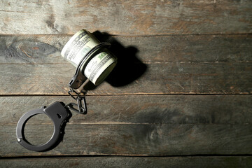 Handcuffs with dollar banknotes on wooden background. Sanctions concept