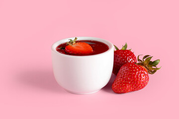 Bowl of sweet strawberry jam on color background