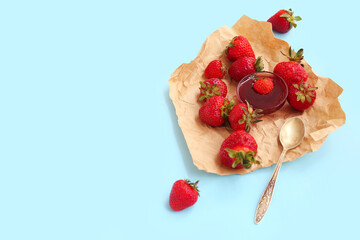 Bowl of sweet strawberry jam and fresh berries on blue background