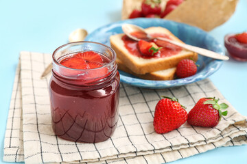 Jar of sweet strawberry jam on blue background