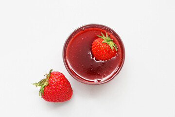 Bowl of sweet strawberry jam on grey background