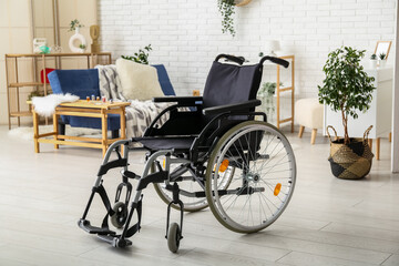 Fototapeta na wymiar Modern empty wheelchair in living room near white brick wall