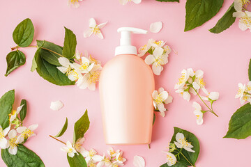 Composition with bottle of cosmetic product and jasmine flowers on pink background
