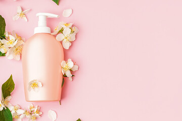 Composition with bottle of cosmetic product and jasmine flowers on pink background