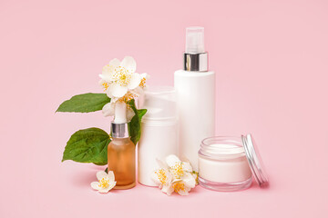 Set of cosmetic products and beautiful jasmine flowers on pink background