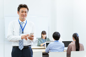 オフィスでスマホを使うアジア人ビジネスマン（中高年男性）

