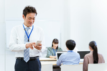 オフィスでスマホを使うアジア人ビジネスマン（中高年男性）
