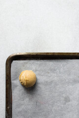 Scoops of vanilla cookie dough on a parchment lined cookie sheet, plain vanilla cookie dough about to be baked