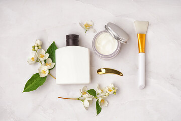 Composition with cosmetic products, spatulas and beautiful jasmine flowers on light background