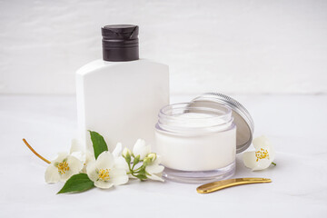 Fototapeta na wymiar Cosmetic products and beautiful jasmine flowers on light background