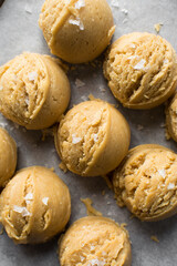 Scoops of vanilla cookie dough on a parchment lined cookie sheet, plain vanilla cookie dough about to be baked