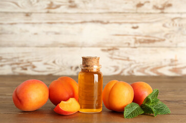 Bottle with cosmetic oil and apricots on wooden table