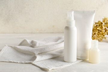 Set of cosmetic products and clean towel on light background
