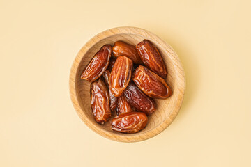 Bowl with dried dates on yellow background