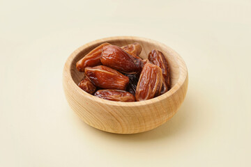 Bowl with dried dates on yellow background
