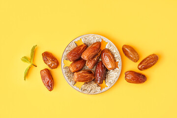 Bowl with dried dates on yellow background