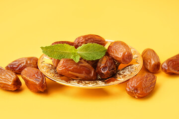 Bowl with dried dates on yellow background