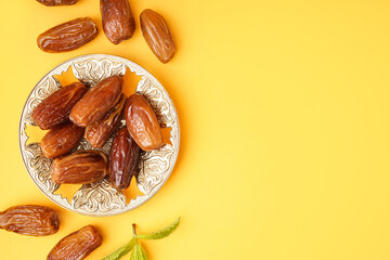Bowl with dried dates on yellow background