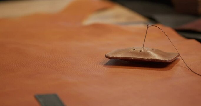Close-up view of female hands inserting needle with thread into pin cushion for embroidery and sewing Clothes designer taking a needle from pincushion, necessary tools for tailor