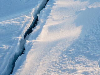 Crack in the ice cover. Snow covered ice. Cracked ice floes on the sea in the Arctic. Polar region.