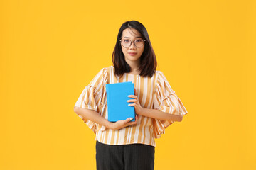 Female Asian Literature teacher with books on yellow background