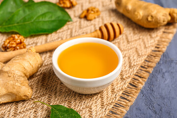 Bowl of sweet honey with walnut and ginger on blue wooden background