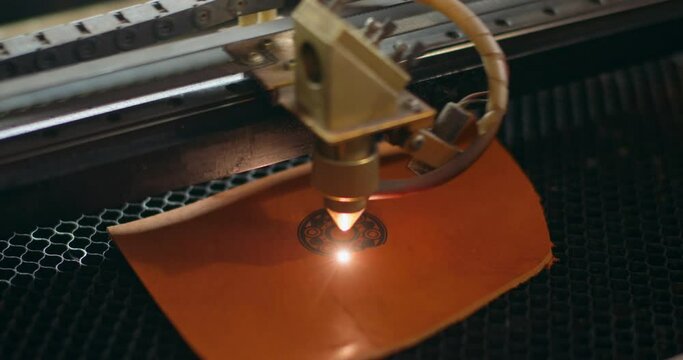 Laser makes engraving on leather wallet , art. slow motion. laser engraver machine working process. decoration of leather accessories, items, close up shot