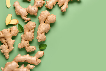 Fresh ginger roots and leaves on green background