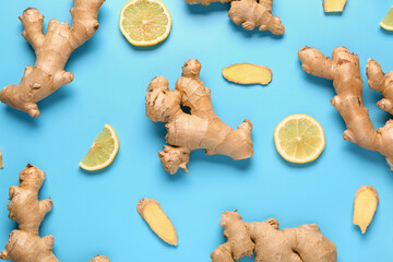 Fototapeta premium Fresh ginger roots with slices of lemon on blue background