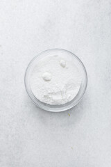 A bowl of white sugar in a glass bowl