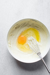 Creamed butter, sugar and egg until pale in a white mixing bowl, the process of making a cake, mixing butter, sugar and egg to make a cake