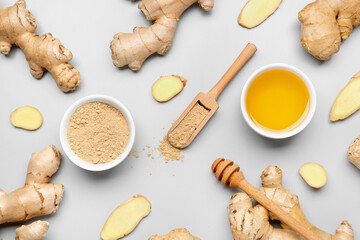 Fresh ginger roots, bowl and wooden scoop with dried powder on grey background