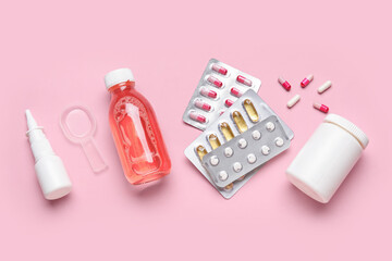 Different pills and bottles of medicines on pink background