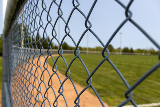 Wire metal fence with baseball field diamond in background. Taken in Toronto, Canada.