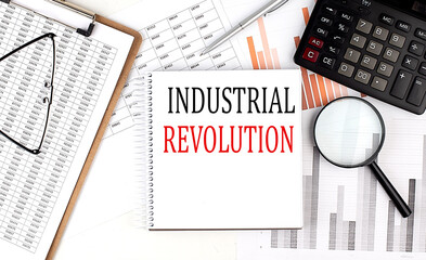 INDUSTRIAL REVOLUTION text on notebook with clipboard and calculator on a chart background