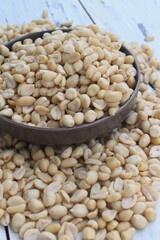 Raw peanuts without skin in a bowl and on a wooden table