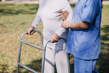 young asian physical therapist working with senior woman on walking with a walker