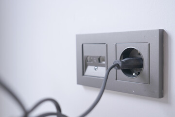  white color power cord cable plugged into wall 