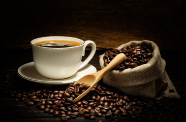 Black coffee or hot tea in a cappuccino espresso cup, breakfast food with coffee beans on a wooden table Isolated on a dark background, top view