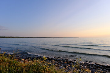 a small boat sails to the shore at sunset