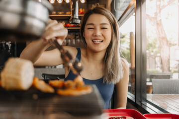 Happy asian woman eating korean grilled buffet in the restaurant.