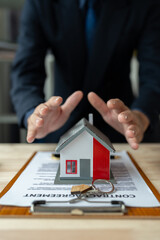 Fototapeta premium Property insurance, real estate broker or home insurance agent gesture protect house, house key, contract document, security concept, protection. Insurance rent buy sell mortgage