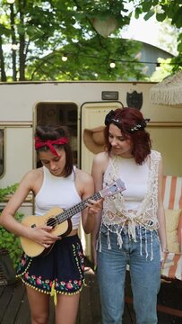 A pair of hippie girls showcasing their musical talents on guitar while singing.