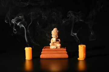 Buddha statue with the smoke of an extinguished candle on the dark background